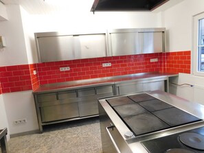 Une cuisine dotée d’un plan de travail en acier inoxydable, d’un crédence en carreaux rouges et d’une cuisinière intégrée.