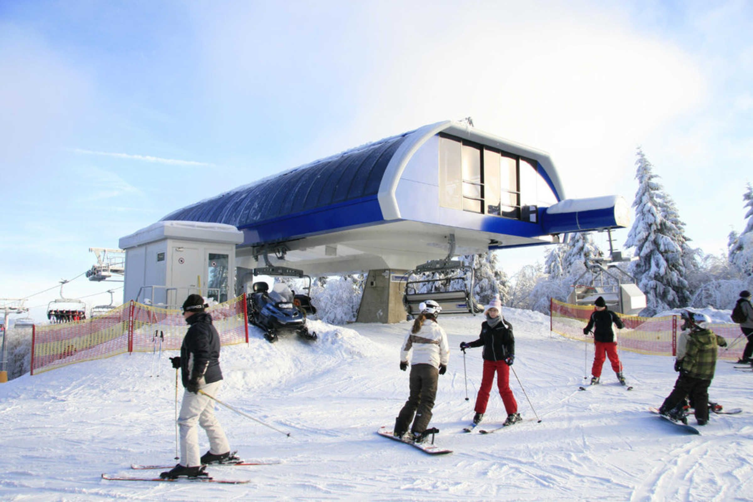 Un complejo de esquí con un edificio moderno, pistas de esquí y árboles cubiertos de nieve.