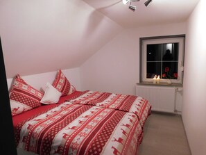 Ein Schlafzimmer mit einem Bett, Kissen, einem Fenster mit Ausblick und einer Nachttischlampe.