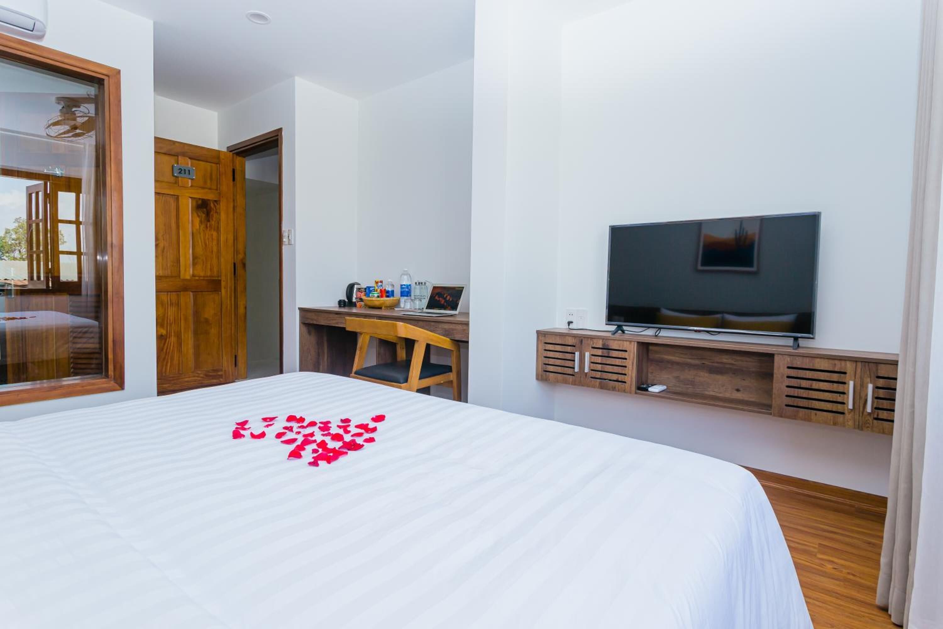 Une chambre à coucher comprenant un lit, un bureau, une télévision et une armoire en bois.