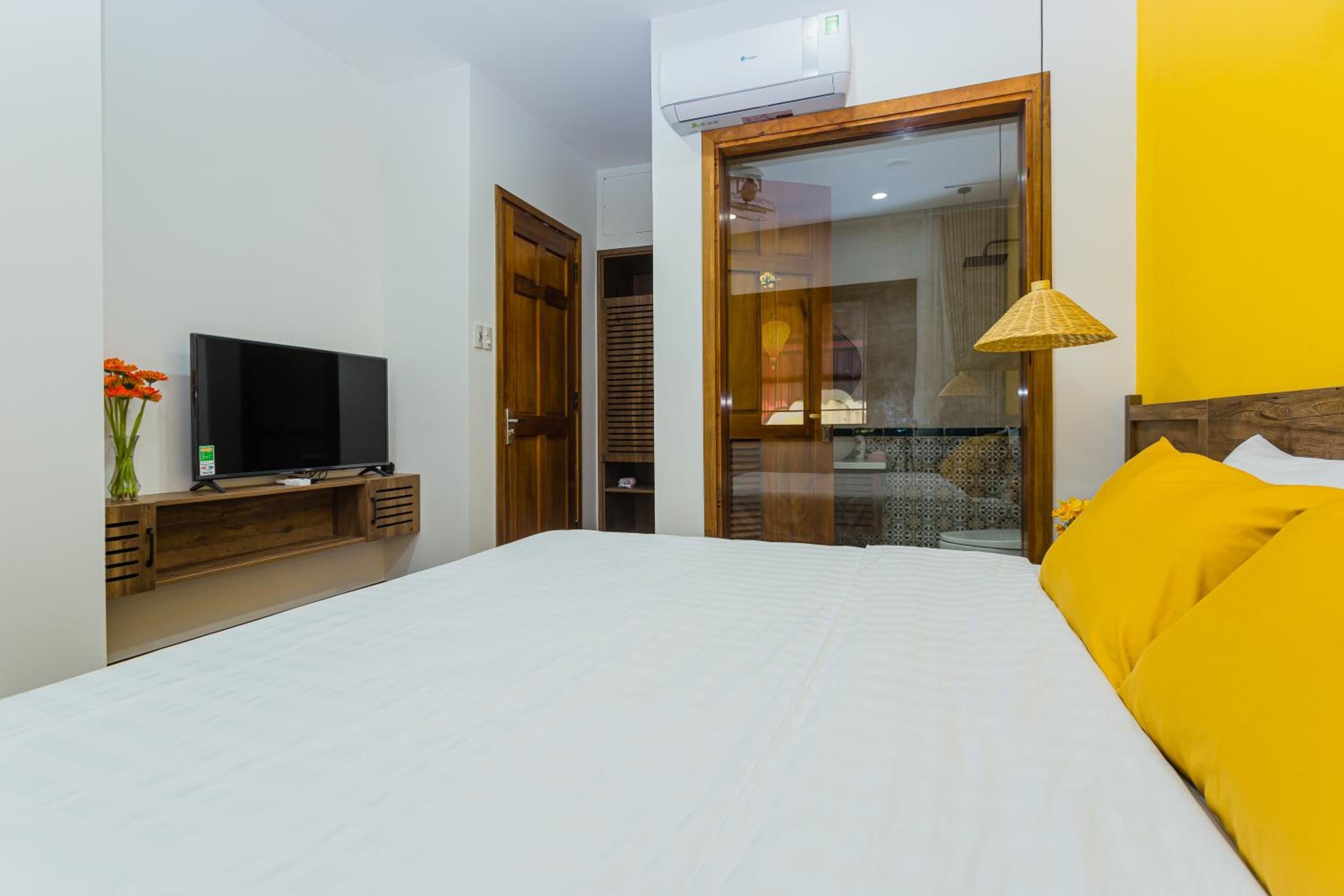 A hotel room with a bed, a television, a wardrobe, and a sliding door to a bathroom.