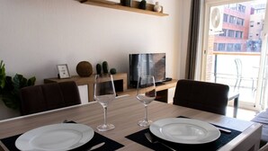 Ein Esstisch gedeckt mit Tellern und Weingläsern, ein Fernseher und eine Pflanze in einem modernen Wohnzimmer.