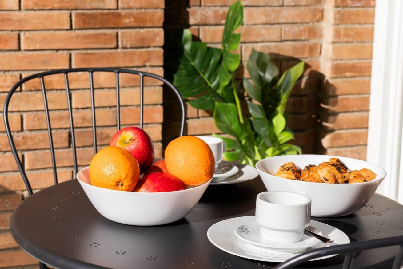 Een tafel met een schaal fruit, een kopje en een bak eten.