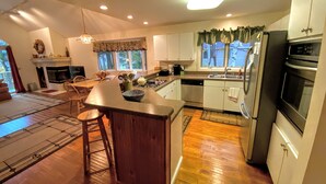A modern kitchen with a central island, stainless steel appliances, and a dining area with a fireplace.