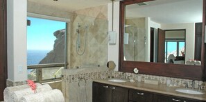 A bathroom with a large mirror, two sinks, a shower, and a view of the ocean. - Oceanfront Mansion with Breathtaking Views of the Pacific, Sunset, Whales and th (Cabo San Lucas)