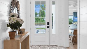 A reception area with a white door, a potted plant, a mirror, and a patterned rug. - ⚓Bay Dreamin! Walk to the Beach, Pier, & Pine Ave! Heated Pool!⚓⛳🏖🌅 (Anna Maria)