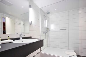 Un bagno moderno con lavandino, specchio e doccia bianchi.