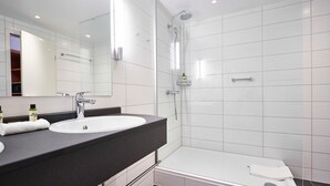 A modern bathroom with a white sink, mirror, and shower.