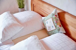 Un letto rifatto con lenzuola bianche e un cuscino decorativo con motivo floreale.