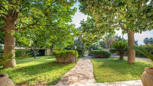 A stone pathway leading through a lush garden with trees and shrubs. - Villa Matilde, with swimming pool, whirlpool and pine forest, beach at 400m (Mazara del Vallo)