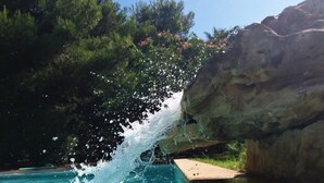 A pool with clear blue water, surrounded by greenery and a rocky cliff. - Villa Matilde, with swimming pool, whirlpool and pine forest, beach at 400m (Mazara del Vallo)