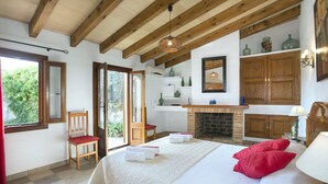 A bedroom with a bed, a chair, a fireplace, and a view of greenery outside. - VILLA TARONGERS - STAY FOR COUPLES (Pollensa)