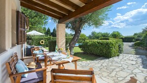 An outdoor patio with wooden furniture, a table set for dining, and a stone pathway leading to a garden. - VILLA TARONGERS - STAY FOR COUPLES (Pollensa)