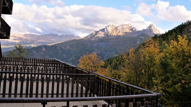 A balcony with a view of a mountain range and autumn foliage. - Studio cabin in Pra-Loup with balcony and mountain view (Pra-Loup)