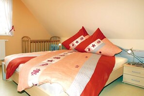 A bedroom with a bed, a bedside table, a lamp, and a window with curtains.