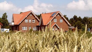 A two-story brick house with a red-tiled roof and a visible solar panel.