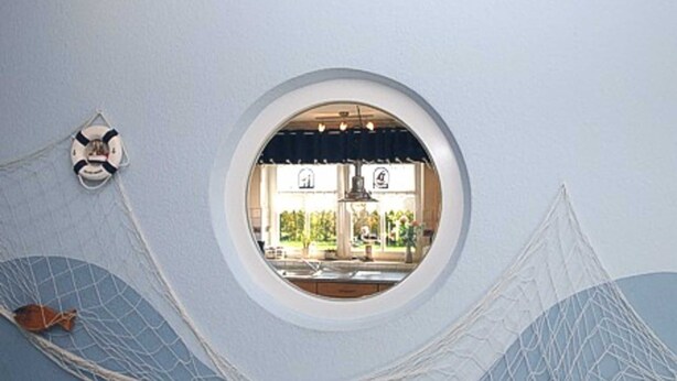 A circular window with a view of a kitchen and dining area.