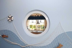 A circular window with a view of a kitchen and dining area.