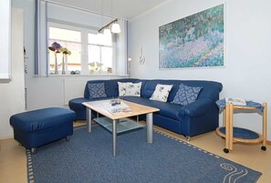 Un salon moderne avec un canapé bleu, une table basse et un panier pour animaux de compagnie.