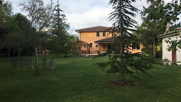 Una casa con un prato curato, un piccolo albero e un gazebo.