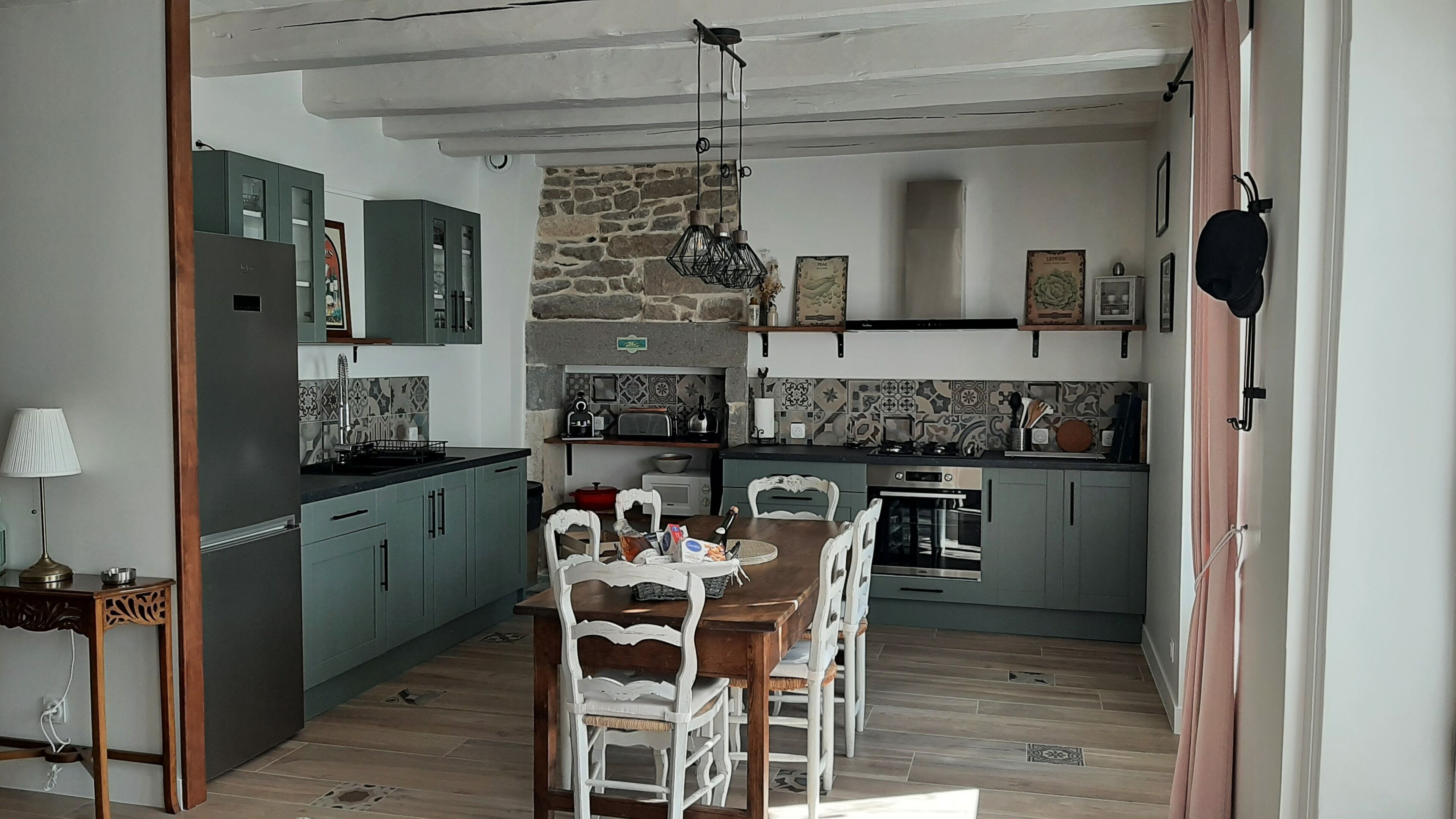 A compact kitchen with a dining area, featuring a stone wall, tiled backsplash, and modern appliances.