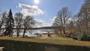 Une vue sur le lac, avec un quai, un bateau en bois et un chalet.