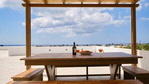Une table en bois, avec une bouteille et des verres, placée devant un ciel dégagé et un paysage lointain.