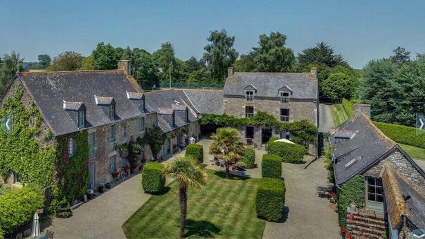 A stone building with a courtyard, featuring a central lawn and several potted plants. - In the grounds of a manor house (Saint Hélen)
