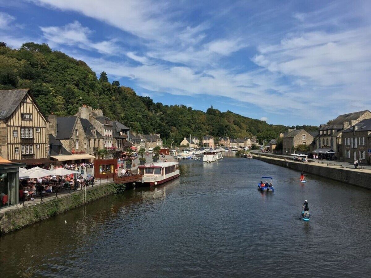 Eine Flussstadt mit historischen Gebäuden, einem anlegenden Boot und einem Fußweg am Flussufer.