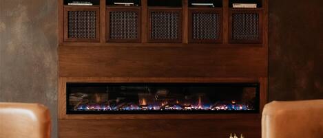 Una zona de estar acogedora con sillones de cuero, una pequeña mesa redonda con un cuenco decorativo y una chimenea empotrada.