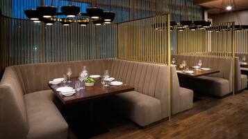 A modern restaurant with booth seating, wooden tables, and pendant lighting.