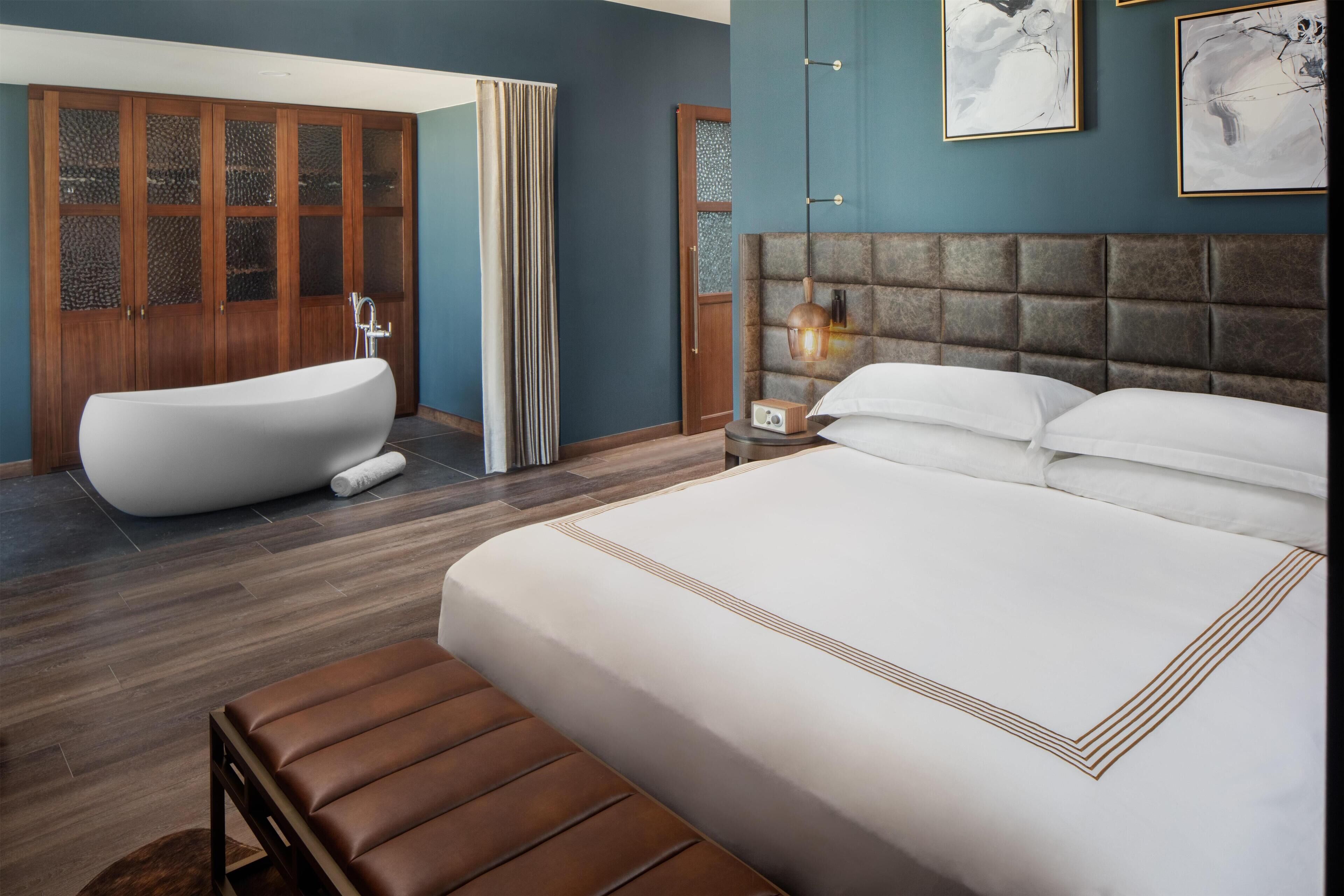 Ein modernes Schlafzimmer mit einem großen Bett, einer Badewanne und einem Holzschrank.