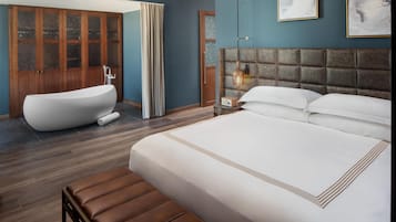 Ein modernes Schlafzimmer mit einem großen Bett, einer Badewanne und einem Holzschrank.