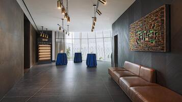 A modern lobby with a leather sofa, a patterned wall art, and a glass partition with a view.