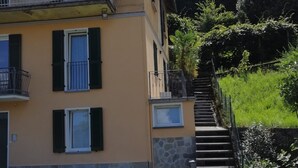 A multi-story building with balconies, a stone staircase, and a well-maintained garden.
