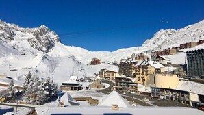 Un pueblo nevado en la montaña, con edificios, una iglesia y un telesilla.