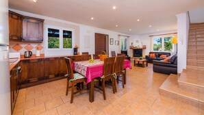 Amplia sala de estar con mesa de comedor, armarios de madera y una escalera que sube a un nivel superior.