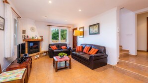 Una sala de estar con dos sofás, una chimenea, un televisor y una escalera.