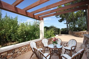 An outdoor patio with wicker chairs and a table, surrounded by stone walls and greenery. - Beautiful Finca Perello with Mountain view (Felanitx)