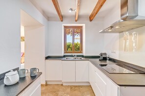 A modern kitchen with white cabinets, a black countertop, a window with a view, and a stainless steel range hood.