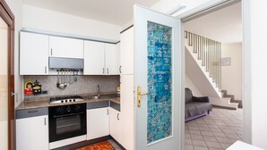 A compact kitchen with white cabinets, a gas stove, and a tiled backsplash.