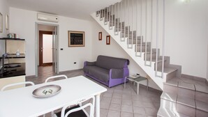A modern living space with a staircase, a dining area, and a sofa.