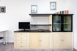 A kitchenette with a TV, a small shelf, and a cabinet with glass doors.