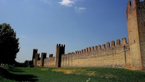 Um muro de pedra histórico com ameias e torres, provavelmente parte de um castelo ou fortificação.