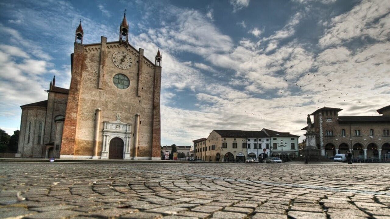A historic building with a clock tower, arched windows, and a cobblestone plaza.