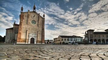 A historic building with a clock tower, arched windows, and a cobblestone plaza.