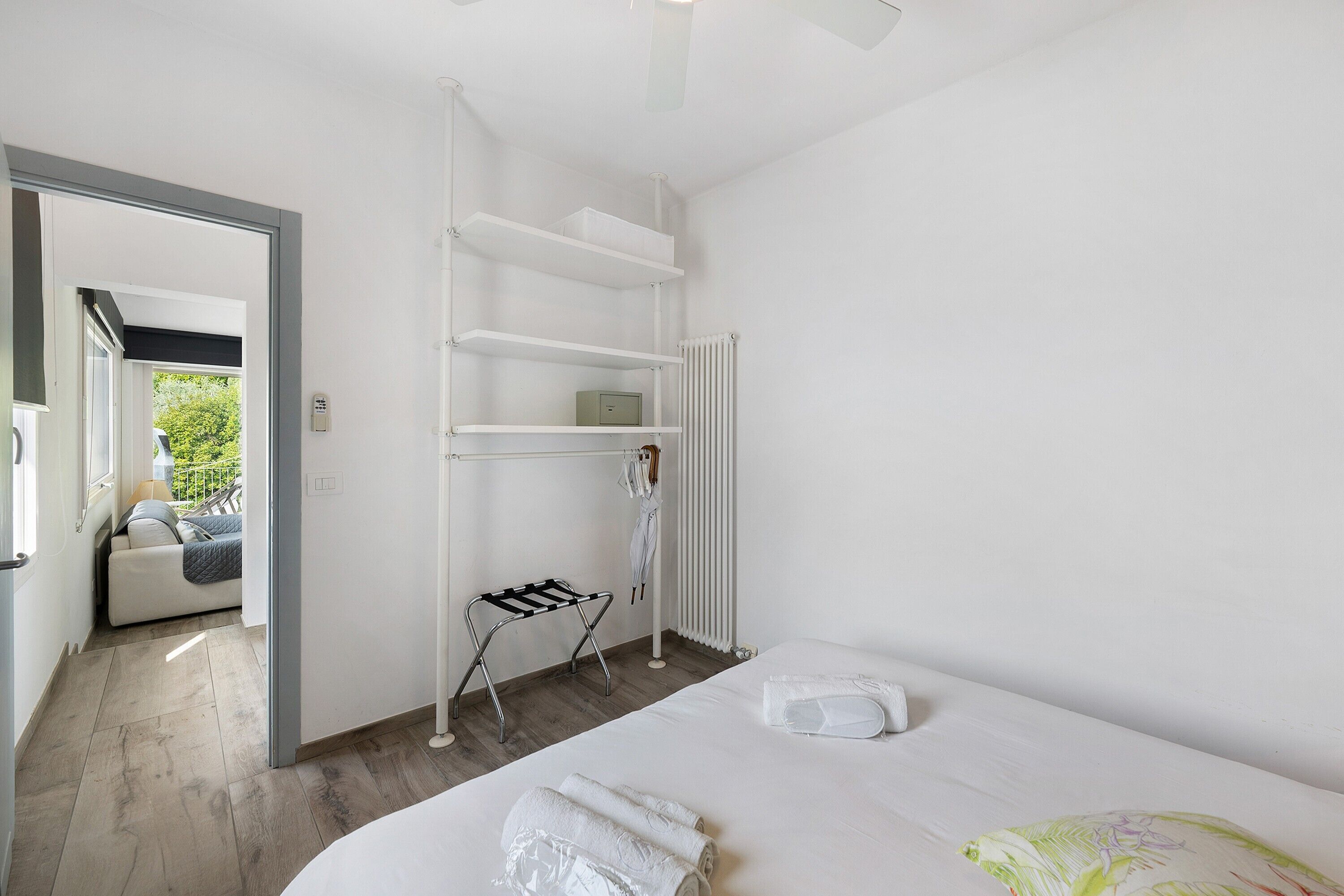 Ein Hotelzimmer mit Bett, Wäscheständer, Heizkörper und Blick auf einen Balkon.
