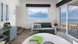 Ein modernes Wohnzimmer mit großem Fenster, einer Couch, einem Tisch und Blick aufs Meer.