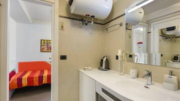Ett hotellbadrum med ett vitt handfat, en spegel, en hårtork och en handduksställning.