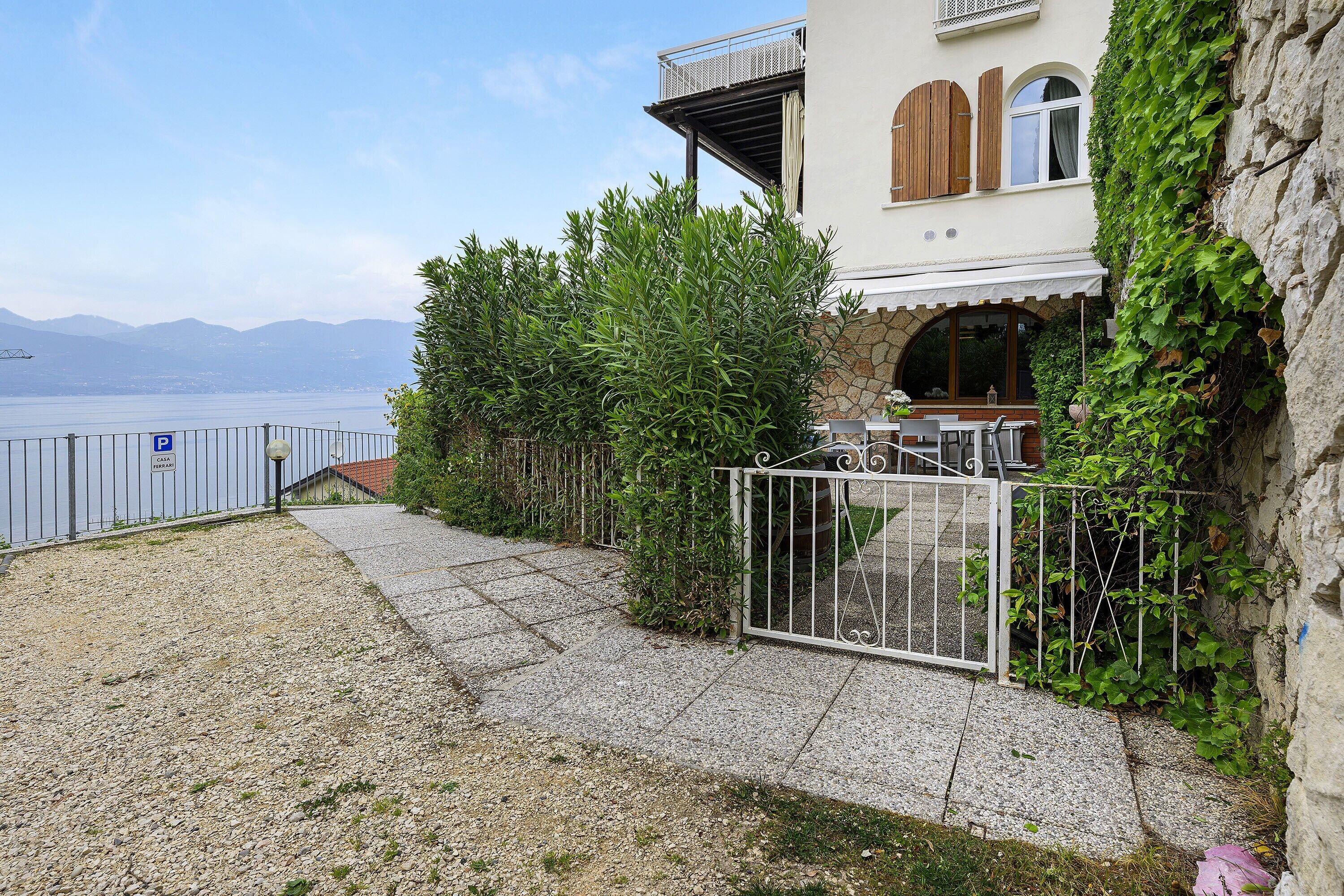 A coastal property with a gravel driveway, a metal gate, and a view of the sea.